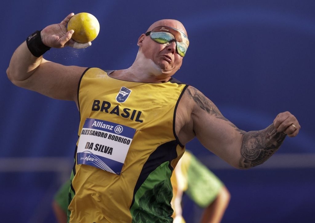 Foto mostra o atleta Alessandro Rodrigo da Silva, enquanto arremessa um peso. Imagem: Alessandra Cabral / CPB.